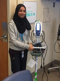 Picture of a student beside a blood pressure monitor